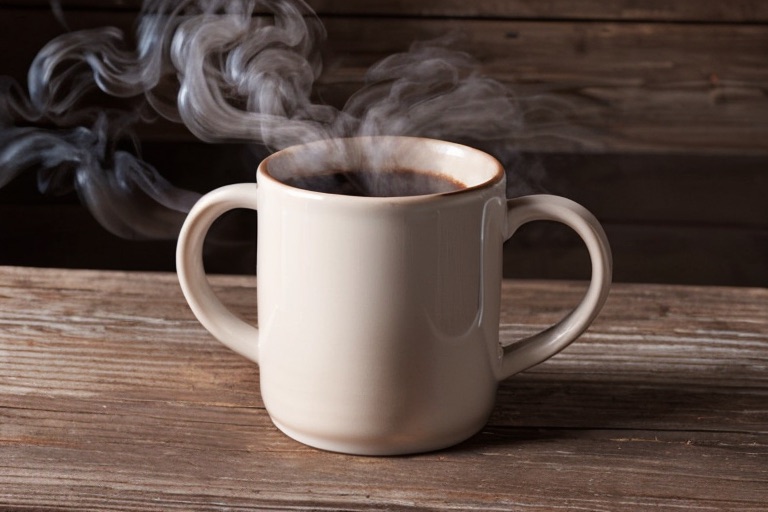 A steaming ceramic mug on a wooden table